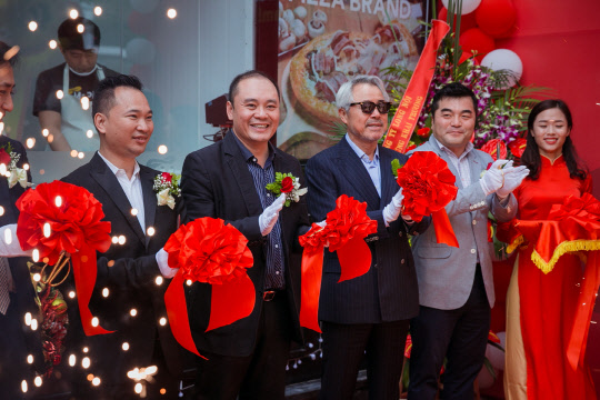 MPK그룹이 지난 24일 베트남 하노이 바찌에우 대로에 미스터피자 베트남 1호점을 개점했다. 이날 오픈 행사에서 정우현 MPK그룹 회장(오른쪽에서 세번째)이 관계자들과 기념 촬영을 하고 있다.  MPK그룹 제공